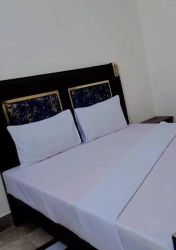 Una cama con sábanas blancas y almohadas en una habitación. en Royal Inn Guest House, en Harīpur