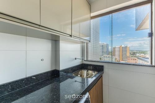 a kitchen with a sink and a large window at Prédio com Piscina a 300m da Praia em Ilhéus - MMD in Pontal de São João da Barra