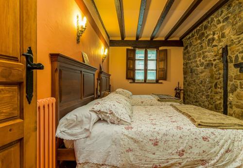a bedroom with a bed and a stone wall at Casa de piedra en el corazón de Potes in Potes