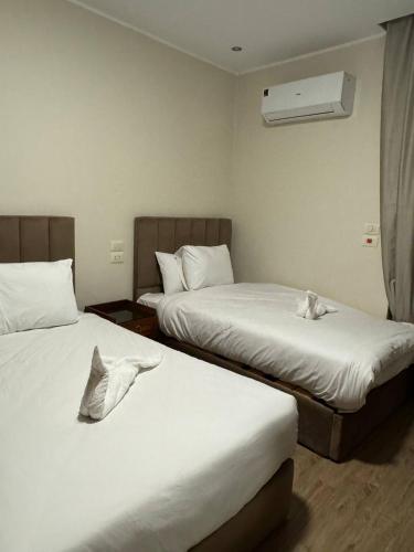 two beds in a hotel room with white sheets at Florya pyramids hotel in Cairo