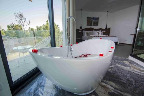 a white bath tub in a room with a window at Enigma - Nature & Water Hotel in São Teotónio
