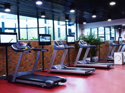 a row of exercise machines in a room with windows at Mercure Beijing Downtown in Beijing