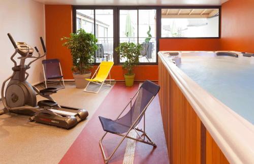 una habitación con un gimnasio con sillas y una cinta de correr en ibis Styles Beaune Centre, en Beaune