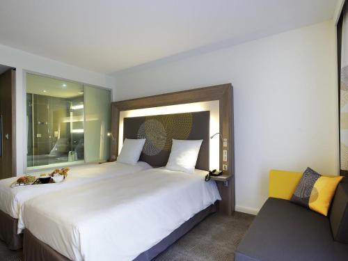 a bedroom with a large white bed and a couch at Novotel Avignon Centre in Avignon