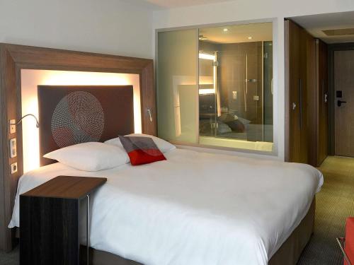 a bedroom with a large white bed with a table at Novotel Avignon Centre in Avignon