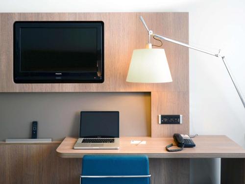 a laptop computer sitting on a desk with a tv at Novotel Avignon Centre in Avignon