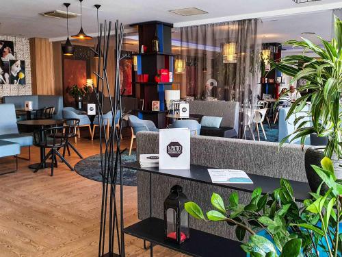 a restaurant with tables and chairs and plants at Novotel Avignon Centre in Avignon