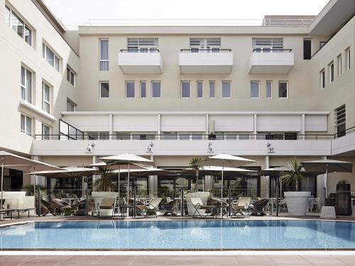 a hotel with a pool and chairs and umbrellas at Novotel Avignon Centre in Avignon