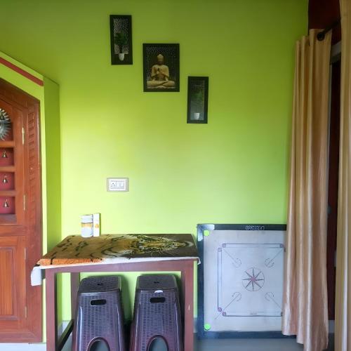 a room with a green wall with a table and two stools at Misty Homes in Madikeri