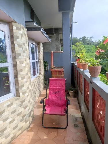 a red chair sitting on a porch with a window at Misty Homes in Madikeri