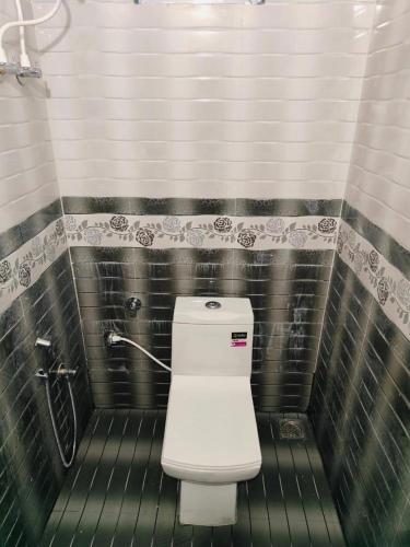 a bathroom with a white toilet in a stall at Misty Homes in Madikeri