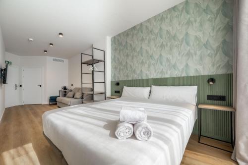a bedroom with a large white bed with two towels at Pensión SÖMN Donostia in Donostia-San Sebastián