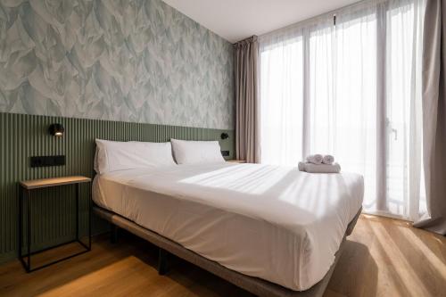 a bedroom with a large bed and a large window at Pensión SÖMN Donostia in Donostia-San Sebastián