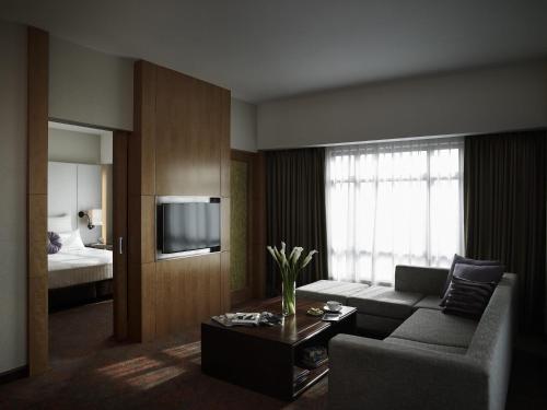 a living room with a couch and a television at Pullman Hanoi in Hanoi