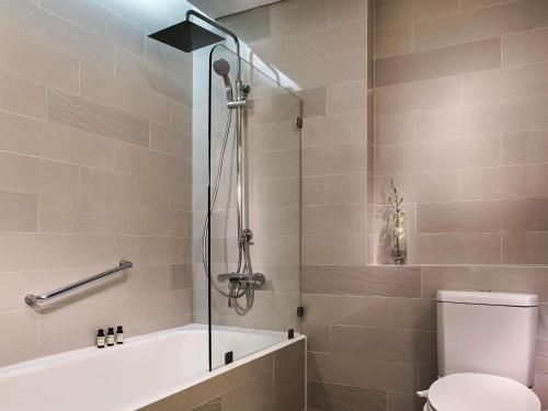 a bathroom with a shower with a toilet and a tub at Pullman Hanoi in Hanoi