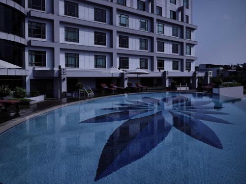 a large swimming pool with an umbrella in front of a building at Pullman Hanoi in Hanoi