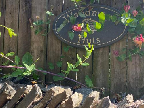 a sign on a wooden fence with some plants at Woodmans Huts in Haverthwaite
