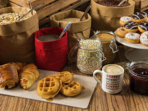 a table with waffles and coffee and other breakfast foods at Ibis Lleida in Lleida