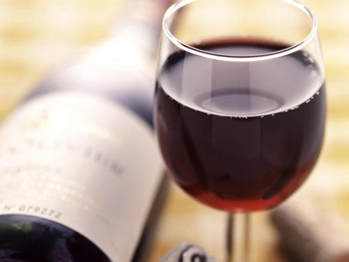 a glass of red wine next to a bottle of wine at Ibis Lleida in Lleida