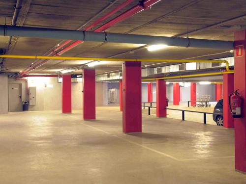 an empty parking lot with red columns in a parking garage at Ibis Lleida in Lleida