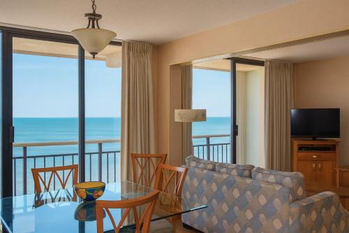a living room with a couch and a table with chairs at Four Sails Resort in Virginia Beach