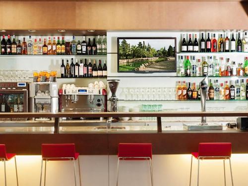 a bar with red chairs and bottles of alcohol at Ibis Budget Lleida in Lleida