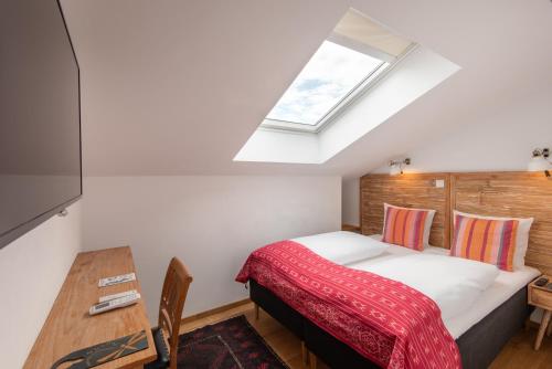 a bedroom with a bed and a table and a skylight at Lulu Guldsmeden in Berlin