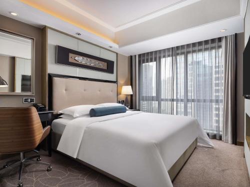 a bedroom with a large white bed and a desk and a window at Pullman Shanghai Jing'an-Jing'an district, downtown railway station, traffic hub, easy to travel Shanghai in Shanghai