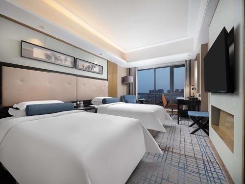 a hotel room with four beds and a flat screen tv at Pullman Shanghai Jing'an-Jing'an district, downtown railway station, traffic hub, easy to travel Shanghai in Shanghai