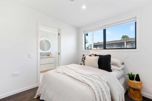 a white bedroom with a bed and a window at Deluxe Queen Room at Wolfe Street in Whangarei