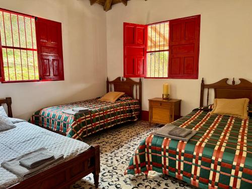 a room with two beds and red windows at Finca cafetera para descanso in Fredonia