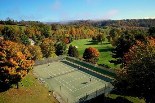 two people playing tennis on a tennis court at Mill Run 3C in Quechee