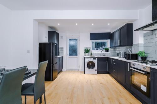 una cocina con armarios negros, lavadora y secadora en 3Bed House-10 Mins to Liverpool, en Bidston