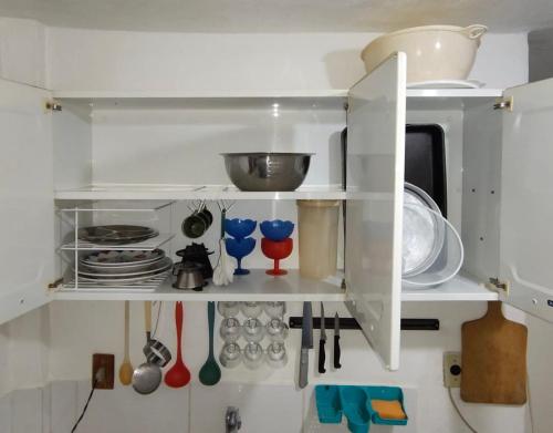 a kitchen with white shelves with utensils at Casa em frente a praça principal in Rio das Flores