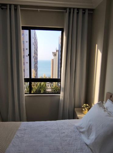 a bedroom with a bed and a large window at Flat Mar Premium 1408 in Fortaleza