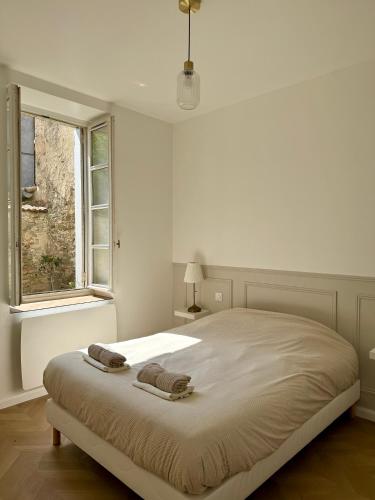 a white bedroom with a large bed with two towels on it at Séjour de charme au cœur de Carcassonne in Carcassonne
