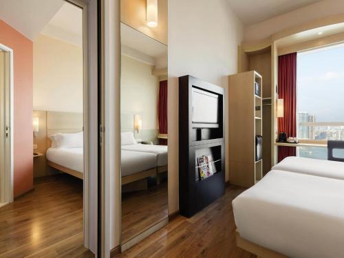 a hotel room with two beds and a mirror at Ibis Hong Kong Central & Sheung Wan in Hong Kong