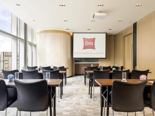 a dining room with tables and chairs and a screen at Ibis Hong Kong Central & Sheung Wan in Hong Kong