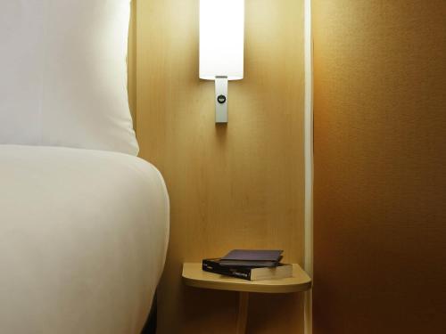 a bedroom with a bed and a night stand with a lamp at ibis London Shepherds Bush - Hammersmith in London