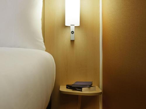 a bedroom with a bed and a night stand with a book at ibis London Shepherds Bush - Hammersmith in London