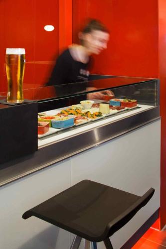a buffet line with food and a man in a beer at ibis London Shepherds Bush - Hammersmith in London