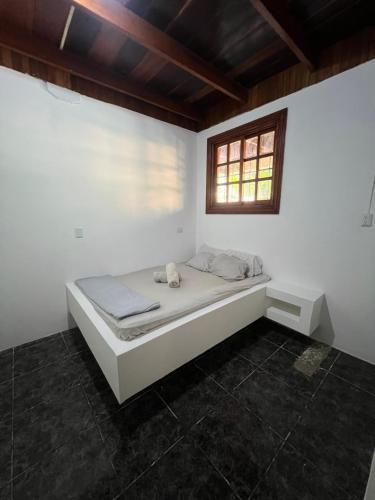 a bed in a white room with a window at Woodstock Hostel in Sámara