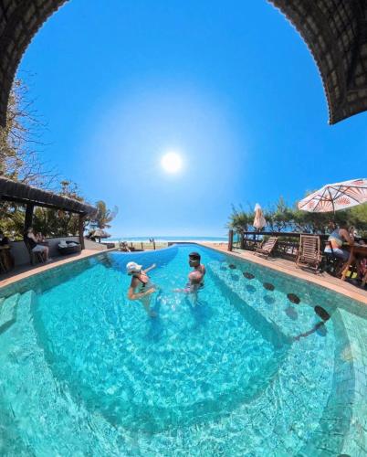 two people in a swimming pool at a resort at Pousada Maracabana Spa in Porto De Galinhas