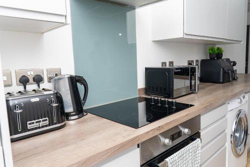 una cocina con encimera con microondas y estufa en 2 Bed Deluxe Apt City Centre, Long stay, en Mánchester