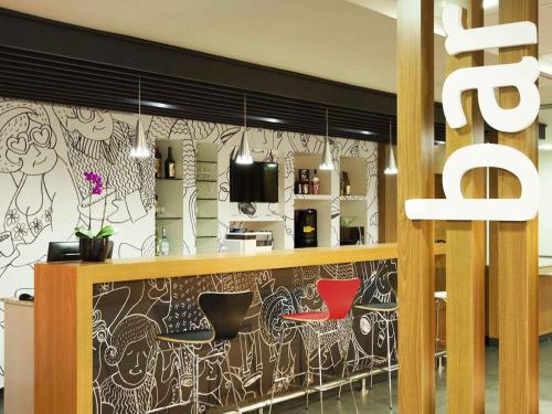 a bar with two red chairs in a restaurant at ibis Cascavel in Cascavel