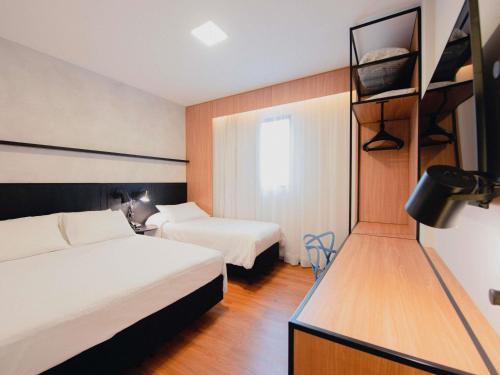 a hotel room with two beds and a tv at ibis Curitiba Shopping in Curitiba