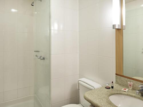 a bathroom with a shower and a toilet and a sink at ibis Curitiba Shopping in Curitiba