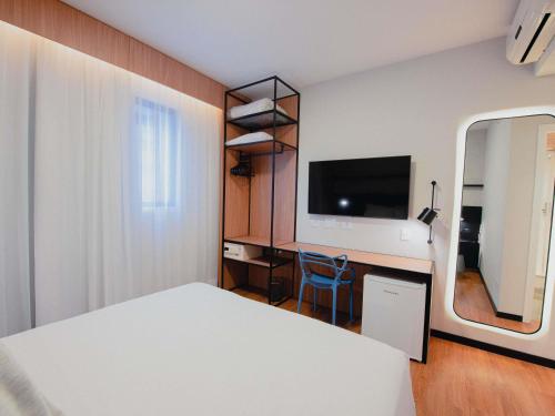 a bedroom with a bed and a desk and a tv at ibis Curitiba Shopping in Curitiba