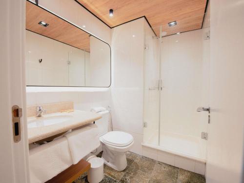 a bathroom with a toilet and a sink and a shower at ibis Curitiba Shopping in Curitiba