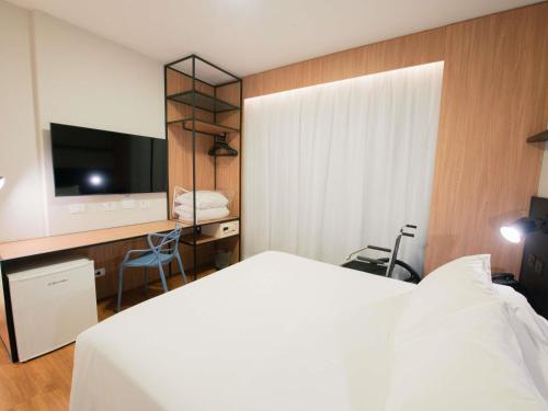 a hotel room with a bed and a tv at ibis Curitiba Shopping in Curitiba